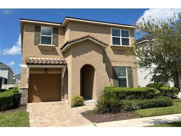 Two-story tan house with a brown door, two-car garage, and manicured landscaping at 1612 Herrons Green Path, Kissimmee, FL 34747