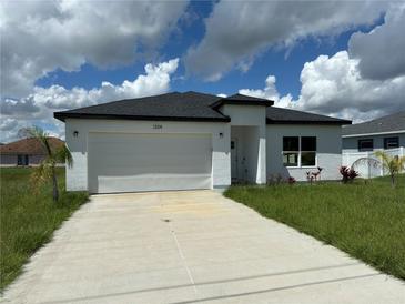 Modern, single story home with a white garage door and driveway at 1204 Vero Beach Way, Poinciana, FL 34759