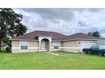 One-story house with a brown roof, tan exterior and a two-car garage at 324 Baccarat Ct, Kissimmee, FL 34759