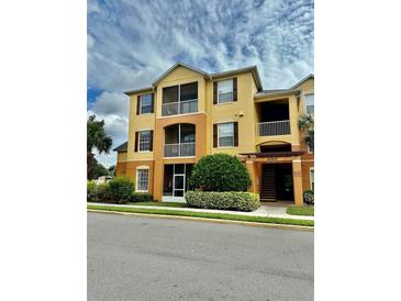 Three-story apartment building with yellow exterior and landscaping at 6265 Contessa Dr # 101, Orlando, FL 32829