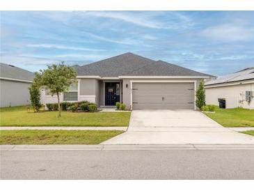 One-story home with gray siding, gray garage door, and landscaping at 872 Sydney St, Davenport, FL 33837