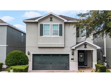 Two-story house with gray siding, dark green garage door, and landscaping at 7617 Brookhurst Ln, Kissimmee, FL 34747