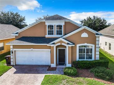 Two-story tan house with a white garage door and landscaped yard at 133 Andalusia Loop, Davenport, FL 33837