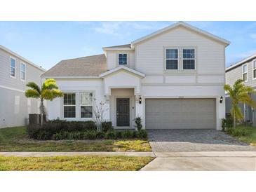 Two-story house with a light-colored facade, a gray garage door, and landscaping at 3525 Lavender Dr, Davenport, FL 33897