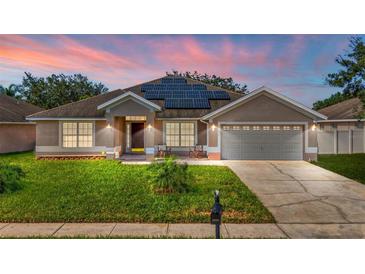 Two-story house with solar panels, a gray garage door, and landscaped yard at 2090 Big Buck Dr, St Cloud, FL 34772