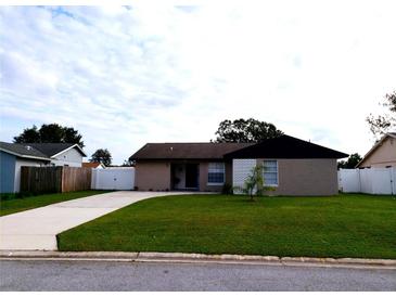 Tan home with a black roof and well-maintained lawn at 449 Ball Ct, Kissimmee, FL 34759