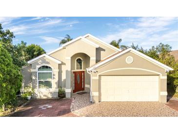 Tan house with a two-car garage and mature landscaping at 223 Lake Davenport Estates, Davenport, FL 33897