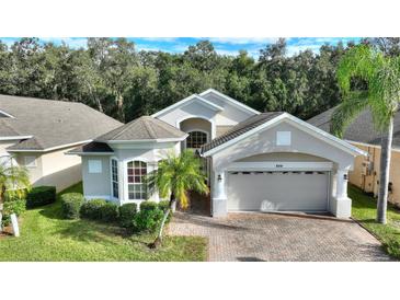 Two-story house with light beige exterior and a two-car garage at 520 Vista Oaks Way, Davenport, FL 33837