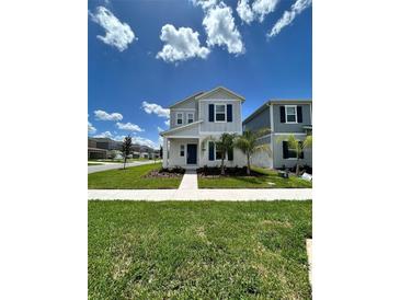 Two-story house with gray siding, blue door, and green lawn at 2893 Fitness St, Clermont, FL 34714