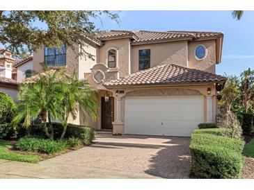 Two story house with beige exterior, attached garage, and manicured landscaping at 7435 Gathering Ct, Reunion, FL 34747