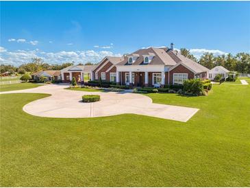 Brick home with circular driveway, landscaping, and detached guest house at 2780 Vickie Ct, Kissimmee, FL 34744