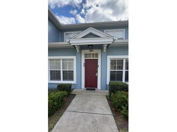 Inviting exterior of a light blue building with a red door and well-manicured landscaping at 2280 San Vital Dr # 105, Kissimmee, FL 34741