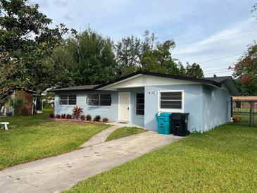 Light blue house with a green lawn and driveway at 4587 Elmira Pl, Orlando, FL 32811