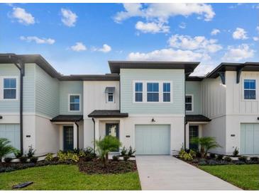 Two-story light teal townhome with attached garage and landscaping at 742 Longboat Dr, Davenport, FL 33896