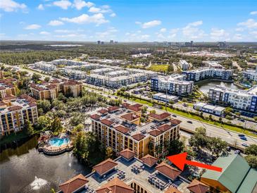 Aerial view of condo building near highway and lake at 12527 Floridays Resort Dr # E-103, Orlando, FL 32821