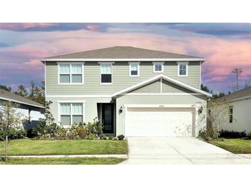 Two-story house with light green vinyl siding, white trim, and a two-car garage at 4963 Royal Point Ave, Kissimmee, FL 34746