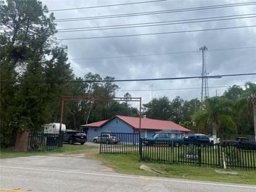Blue house with red roof, gated driveway, and several vehicles at 1808 S Tanner Rd, Orlando, FL 32820