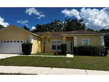 Single-story house with attached garage, landscaping, and a yellow exterior at 481 Peppermill Cir, Kissimmee, FL 34758