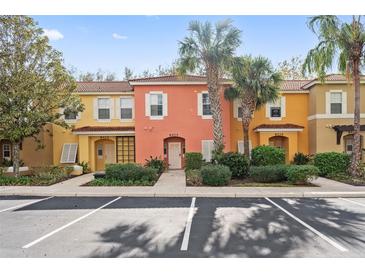 Attractive townhome with orange stucco, white trim, and palm trees at 8404 Crystal Cove Loop, Kissimmee, FL 34747
