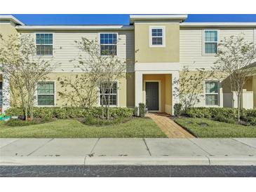 Two-story townhome with light beige siding, landscaping, and a paved walkway at 439 Annabelle Way, Davenport, FL 33837
