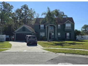 Two-story house with a green exterior, two-car garage, and palm trees at 2350 Chadwick Cir, Kissimmee, FL 34746