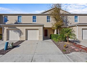 Tan two-story townhome with two-car garage and landscaping at 355 Highcrest Rd, Davenport, FL 33896