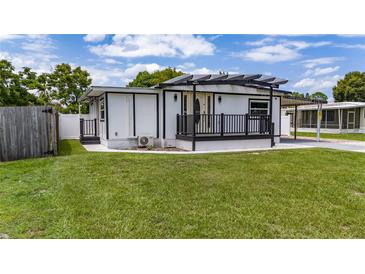 White single-story home with a modern facade, deck and landscaped lawn at 6901 Salinas Dr, Orlando, FL 32822