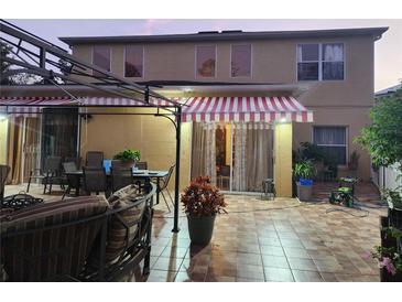 Spacious backyard patio with striped awning, seating area, and tile flooring at 2606 Royal Fern Pl, Kissimmee, FL 34758