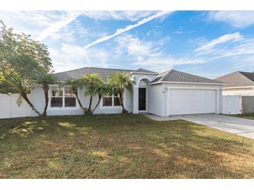 One-story house with a white exterior, gray roof, and a two-car garage at 557 Dove Ct, Kissimmee, FL 34759