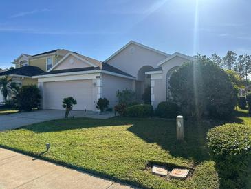 Single-story home with attached garage, manicured lawn, and lush landscaping at 846 Troon Cir, Davenport, FL 33897