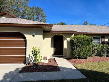 Tan house with brown garage door, walkway, and landscaping at 4724 Pine Lake Dr, Saint Cloud, FL 34769