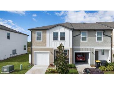 Two-story townhome with attached garage and small front yard at 445 Madison Dr, Davenport, FL 33837