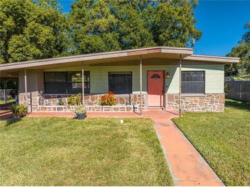 Ranch style home with a coral door, stone accents, and a carport at 309 Poinciana Cir, Kissimmee, FL 34744