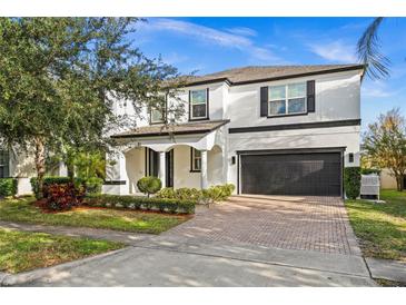 Two-story house with a white exterior, black accents, and a paved driveway at 9111 Outlook Rock Trl, Windermere, FL 34786
