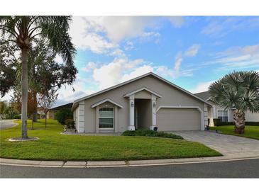 Tan house with palm trees, two-car garage, and landscaped lawn at 504 Ridge View Dr, Davenport, FL 33837