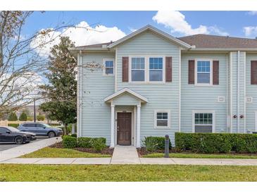 Two-story light-blue townhome with a front yard and walkway at 8984 Silver Pl, Kissimmee, FL 34747