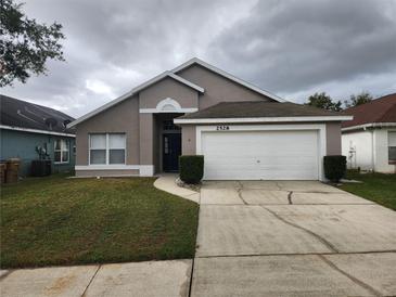 Front exterior of a single-story home with attached garage and landscaped yard at 2528 Chatham Cir, Kissimmee, FL 34746