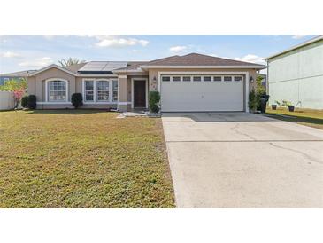 Front exterior of a single-story home with a two-car garage and solar panels at 622 Parakeet Ct, Kissimmee, FL 34759