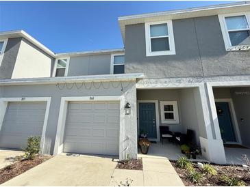Two-story townhome with gray exterior, two-car garage, and front porch at 1861 Roosevelt Pl, St Cloud, FL 34769