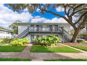 Two-story building with grey stairs and balconies, surrounded by lush landscaping at 4860 Conway Rd # 56, Orlando, FL 32812