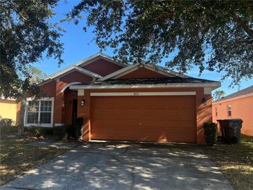 Orange one-story house with a two-car garage and a well-maintained lawn at 922 Sandy Ridge Drive Dr, Davenport, FL 33896