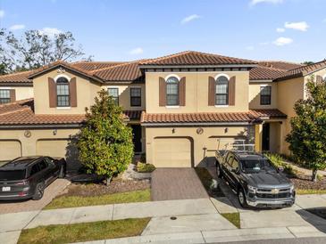 Two-story townhome with tile roof, two-car garage, and landscaping at 8121 Roseville Blvd, Davenport, FL 33896
