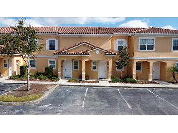 Two-story townhouses with Spanish-style architecture, featuring light-colored exteriors and lush landscaping at 2627 Bugatti Ct, Kissimmee, FL 34746