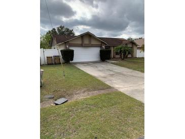 Single-story house with a two-car garage and a well-maintained lawn at 306 Medina Ct, Kissimmee, FL 34758