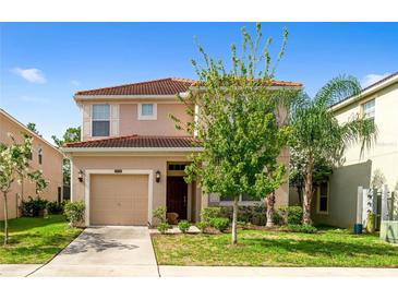 Two-story house with tan exterior, two-car garage, and landscaping at 8958 Sugar Palm Rd, Kissimmee, FL 34747
