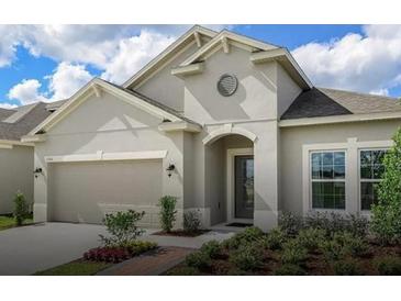 One-story home with light beige exterior, two-car garage, and landscaping at 3306 Sagebrush St, Harmony, FL 34773