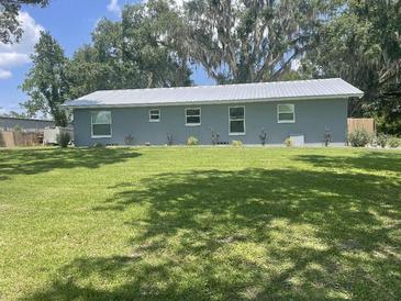 Gray house with metal roof, spacious lawn, and large trees at 4040 Ne 95Th Rd, Wildwood, FL 34785