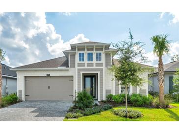 Two-story house with a gray and beige exterior, landscaped lawn, and a two-car garage at 128 Mosaic Blvd, Daytona Beach, FL 32124