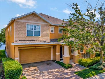 Two-story house with orange siding, a two-car garage, and lush landscaping at 625 Legacy Park Dr, Casselberry, FL 32707