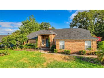 Brick house with a gray roof and nicely landscaped lawn at 10421 Mesa, Clermont, FL 34711